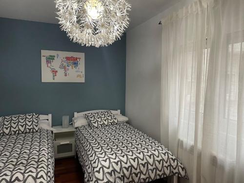 een slaapkamer met 2 bedden en een kroonluchter bij Apartamento corredoira in Monforte de Lemos