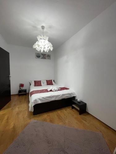 a white bedroom with a bed and a chandelier at BUTTERFLY FAMILY APARTMENT SIBIU in Sibiu