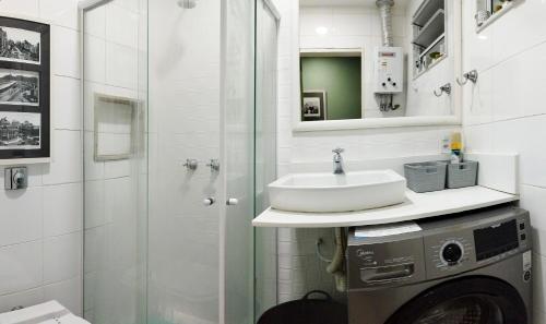 y baño con lavabo, ducha y lavadora. en Loft, en Río de Janeiro