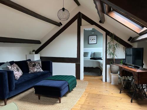 a living room with a blue couch and a bedroom at The Loft, 1 Bedroom flat in rural village in Lockton