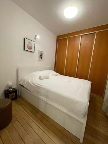 a bedroom with a white bed with a wooden headboard at Paris15 eme Chic appartement atypique et calme in Paris