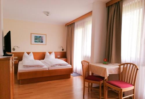 pokój hotelowy z łóżkiem, stołem i krzesłami w obiekcie Strandpension Liane w mieście Sankt Kanzian