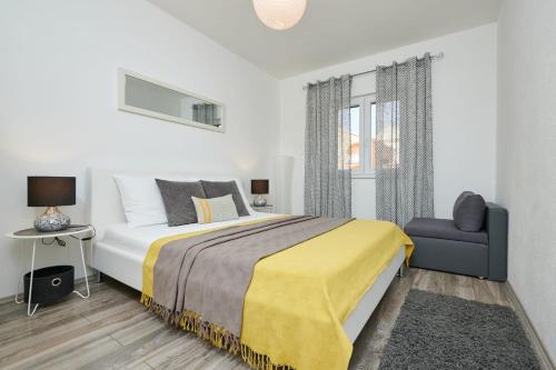 ein weißes Schlafzimmer mit einem großen Bett und einem Stuhl in der Unterkunft Villa Demonta in Trogir
