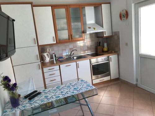 una cocina con armarios blancos y una mesa. en Apartment in Lovran with terrace, air conditioning, WiFi, washing machine 3735-2 en Lovran