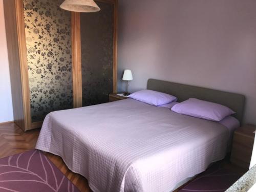 1 dormitorio con 1 cama blanca grande con almohadas moradas en Apartment in Lovran with terrace, air conditioning, WiFi, washing machine 3735-2 en Lovran