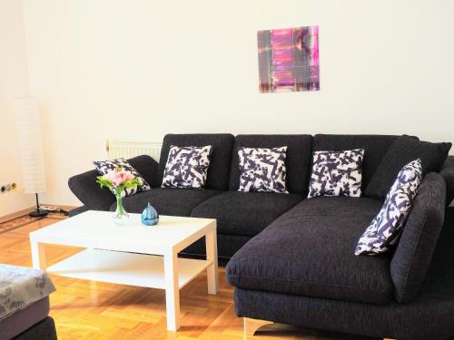 a living room with a black couch and a white table at City Villa Schönbrunn Apartments - Contactless 24h Check-In in Vienna