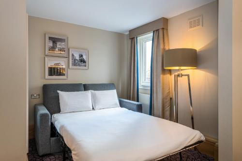 um quarto de hotel com uma cama, um candeeiro e uma janela em The Scholar em Edimburgo