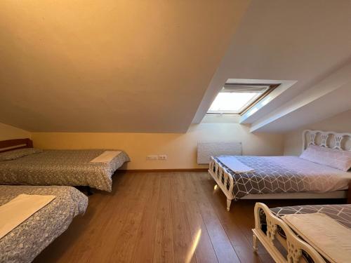 Cette chambre comprend 3 lits et une lucarne. dans l'établissement ApartamentosArturo Llanes LaPlaza Atico céntrico, à Llanes