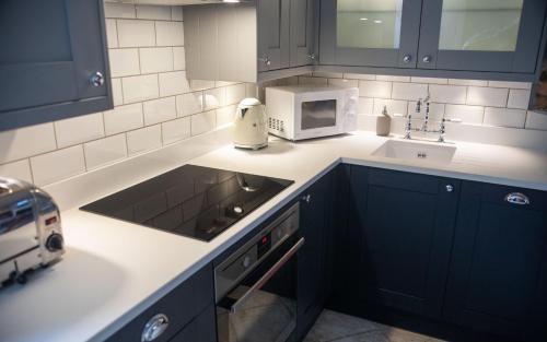 a kitchen with blue cabinets and a sink and a microwave at Brakestone Cottage in the heart of Port Isaac in Port Isaac