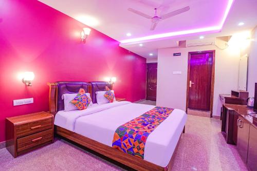 1 dormitorio con 1 cama grande y pared de color rosa en FabHotel Turning Point - Nr Ulsoor Lake, en Bangalore