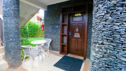 a door with a table and chairs next to a stone wall at Aberdare Prestige & Royal Cottages in Nanyuki