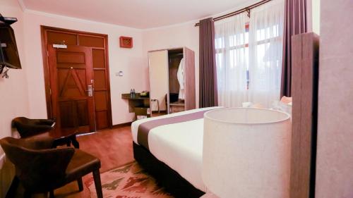 a hotel room with a bed and a desk and a window at Aberdare Prestige & Royal Cottages in Nanyuki