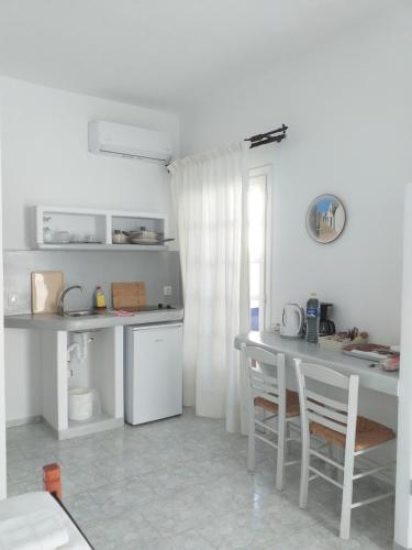 a white kitchen with a table and chairs in it at Captain Stavros in Pollonia