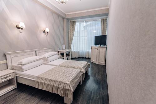 um quarto de hotel com uma cama e uma televisão em Gold Georg Palace Hotel em Chernivtsi