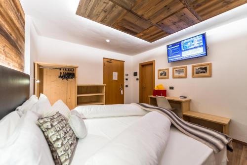 a bedroom with two beds and a tv on the wall at Alpstyle Hotel Albolina Wellness & Beauty in Canazei