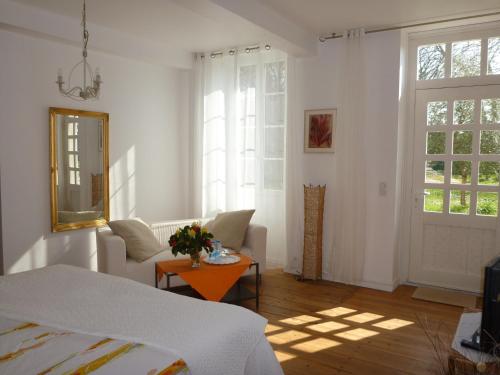 Cette chambre blanche dispose d'un lit, d'une table et d'une fenêtre. dans l'établissement Domaine du Papillon, à Lesparre-Médoc