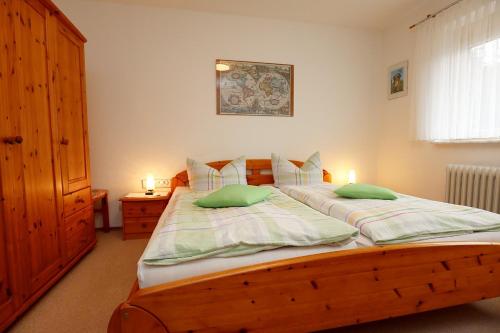 een slaapkamer met een houten bed met 2 groene kussens bij Haus Gerlinde in Zell am Harmersbach