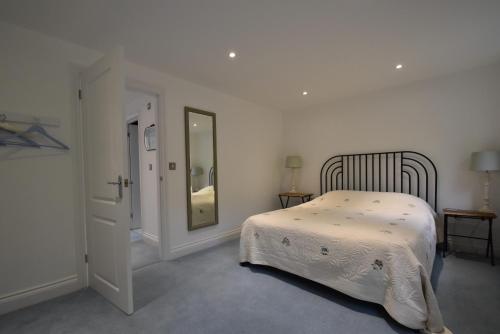 a white bedroom with a bed and a mirror at Southbank in Rye