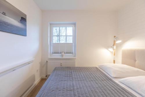 a white bedroom with a bed and a window at Seestern in Vollerwiek