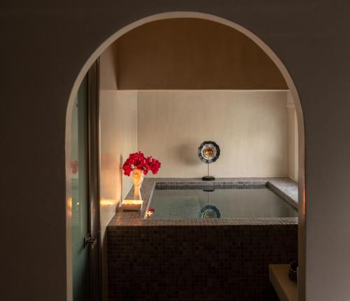 a bathroom with a bath tub with a vase of flowers at Centro Suite in Imerovigli