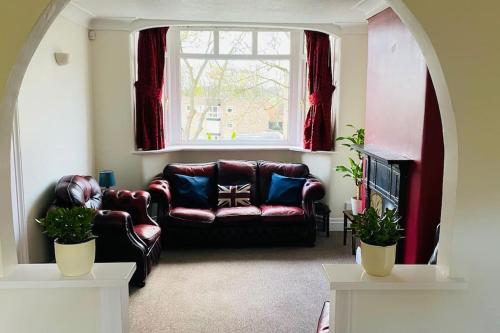 a living room with a leather couch and a window at 3 BR Property in Prestwich 15 mins from Manchester City Centre Garden Free parking Superfast WIFI Netflix in Manchester