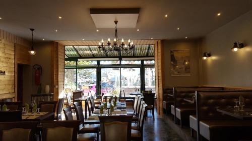 une salle à manger avec des tables et des chaises ainsi qu'un lustre dans l'établissement Hôtel Restaurant Glaizette, à LʼArgentière-la-Bessée