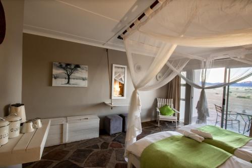 a bedroom with a canopy bed and a window at Elegant Desert Lodge in Sesriem