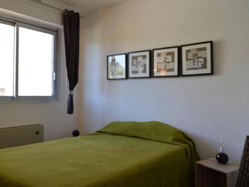 - une chambre avec un lit vert et trois photos sur le mur dans l'établissement Appartement 3 pièces, piscine, à 100m de la plage, avec garage privatif, Cap d'Agde - FR-1-249-192, au Cap d'Agde