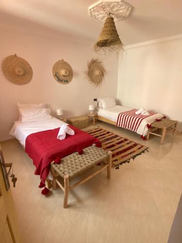 a bedroom with two beds and a red blanket at Moana Surf Maroc in Tamraght Ouzdar