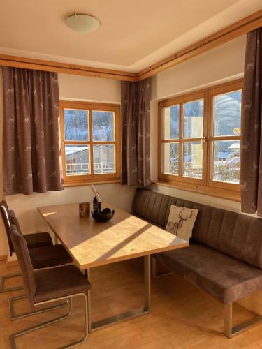 a dining room with a bench and a table and windows at Landhaus Rosengartl Krimml in Oberkrimml
