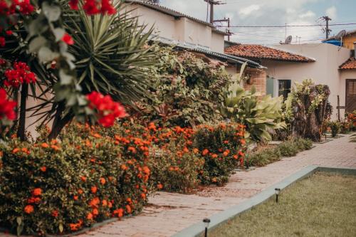 a garden with red flowers next to a house at Free! Hostel Vila in Pipa