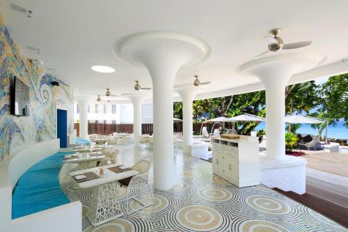 a restaurant with white columns and a tile floor at Savoy Seychelles Resort & Spa in Beau Vallon