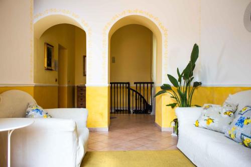 un soggiorno con 2 divani bianchi e una pianta di Badia Holiday Home a Taormina