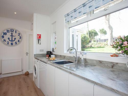 a white kitchen with a sink and a window at Blue Horizon in Sidmouth