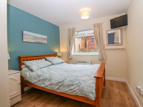 a bedroom with a bed with blue walls and a window at Stepping Stones 1 in Pwllheli