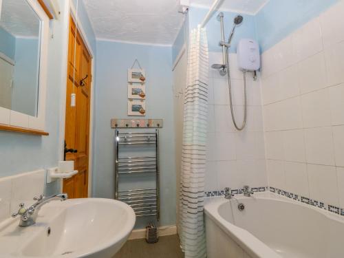 a bathroom with a sink and a tub and a shower at Stepping Stones 1 in Pwllheli