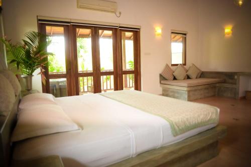 a bedroom with a large white bed and a desk at Kingfisher Bamboo Garden Villa in Unawatuna
