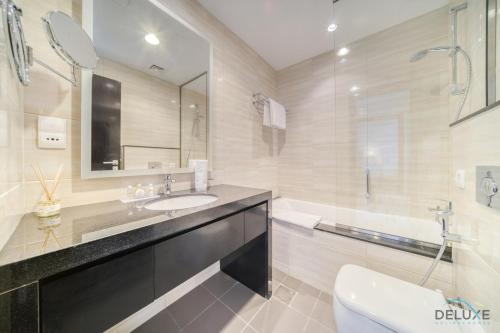 a bathroom with a sink and a toilet and a tub at Urban 1BR at DAMAC Celestia B Dubai South by Deluxe Holiday Homes in Dubai