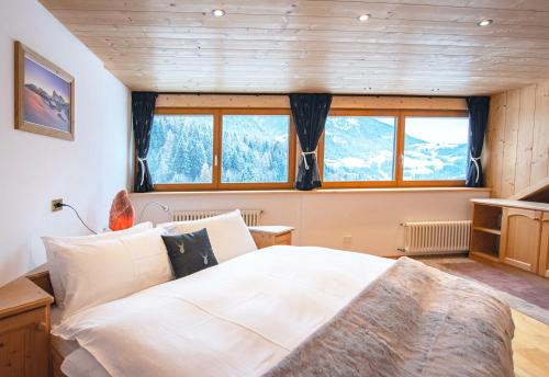 - une chambre avec un grand lit blanc et des fenêtres dans l'établissement Mountain Living Apartment Idylia, à Ortisei