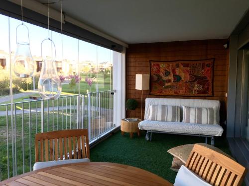 Habitación con balcón, sofá y mesa. en Coqueto Apto Con Vistas En Las Margas Golf n001, en Sabiñánigo