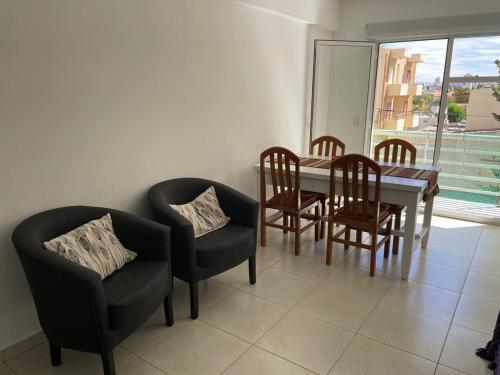 comedor con mesa, sillas y ventana en Hermoso Departamento céntrico a 50mts del mar en Puerto Madryn