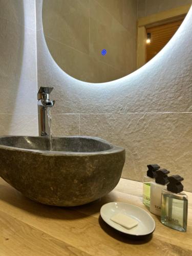 y baño con lavabo de piedra y espejo. en Fonda Peremiquel, en Castellar de NʼHug