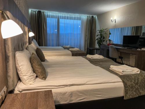 a hotel room with three beds and a desk at Katalina SPA Resort in Tsigov Chark