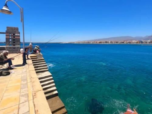 a group of people fishing on a pier in the water at Cosy apartment near the beach in Arinaga