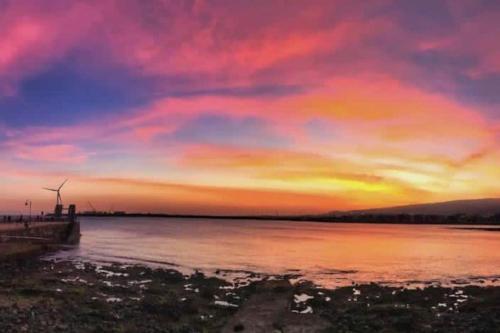 a sunset over a body of water with a windmill at Cosy apartment near the beach in Arinaga