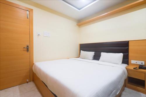 1 dormitorio con 1 cama blanca grande y puerta de madera en FabExpress Ganpati 2 en Siliguri