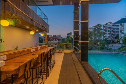 um bar com mesas e cadeiras ao lado de uma piscina em Moustache Rishikesh Luxuria em Rishikesh