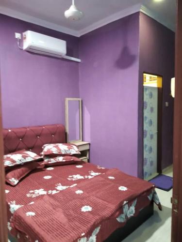 1 dormitorio con paredes moradas y 1 cama con colcha roja en D'illahs Homestay, en Alor Setar
