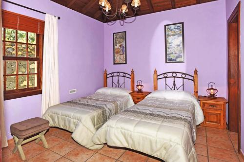 Las TriciasにあるCasa Aljibe 1の紫の壁のベッドルーム1室(ベッド2台付)