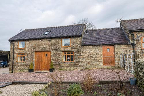 a stone house with wooden doors and a yard at Brambles Farm in Leek